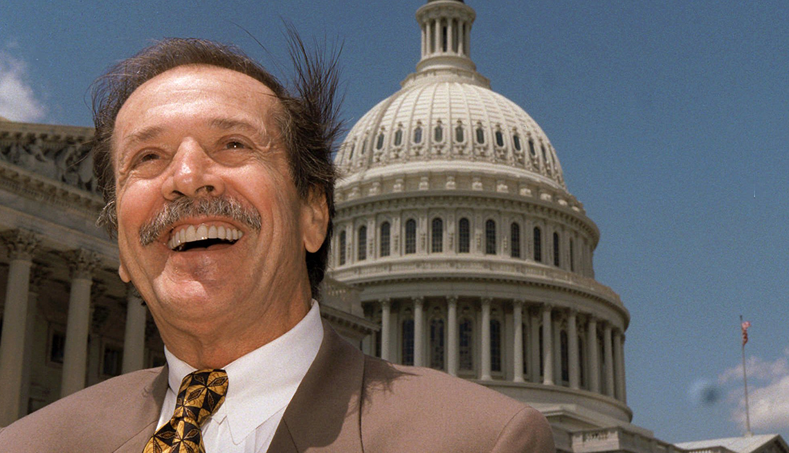 item 27 of Gallery image - Sonny Bono smiles as the wind blows his hair under a blue sky in front of the US Capitol building