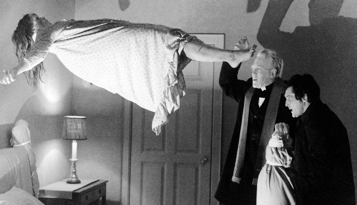 item 6 of Gallery image - Regan MacNeil is elevated from a bed while Father Lancaster Merrin and Father Damien Karras look on during a scene from 'The Exorcist'