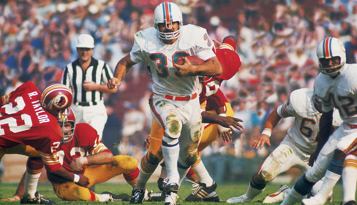 Miami Dolphins fullback Larry Csonka carries the football through teammates as well as opposing members of the Washington Football Team