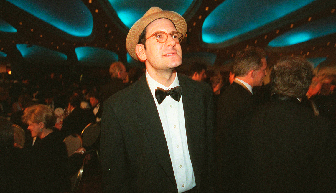 item 15 of Gallery image - Matt Drudge wears glasses, a fedora and a tuxedo while looking up in the air with a formal party in the background