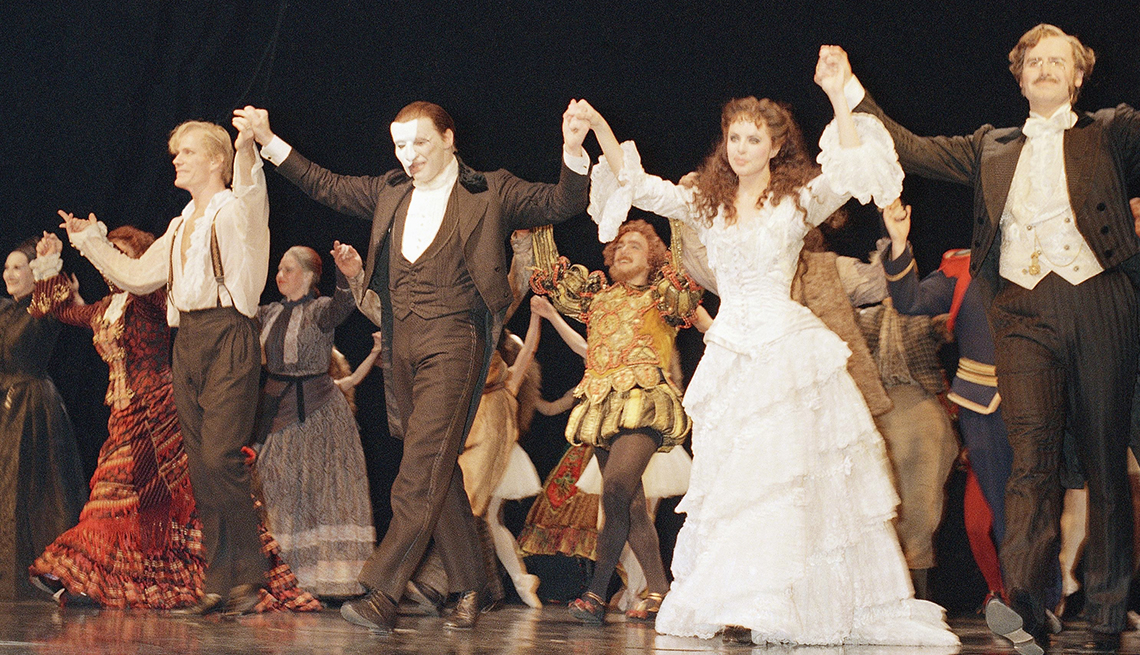 The cast of 'Phantom of the Opera' in costume holding hands before taking a bow on stage