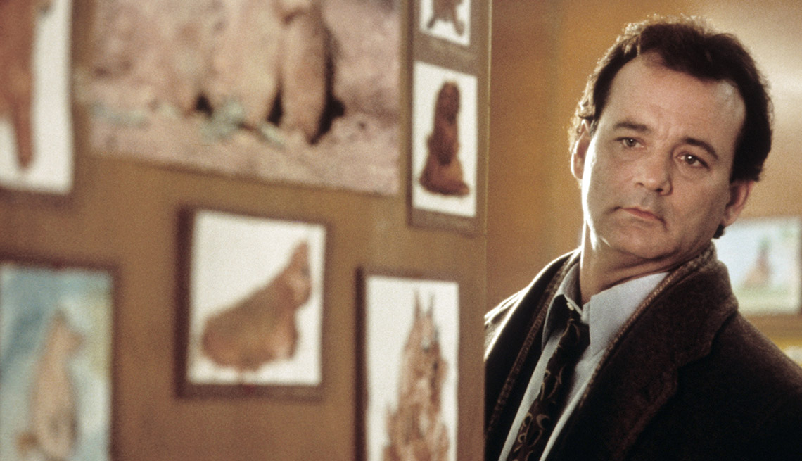 item 17 of Gallery image - actor Bill Murray peers around a corner at a wall decorated with pictures of groundhogs