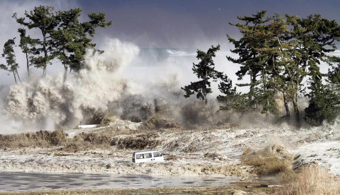 item 21 of Gallery image - a white vehicle is nearly lost as tsunami waves strike a tree-lined coastal area in japan