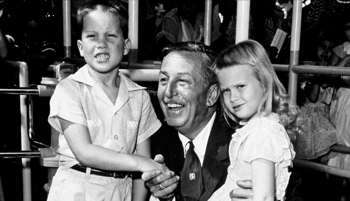 item 15 of Gallery image - Walt Disney poses with the first two visitors, Michael Schwartner, 7, left, and Christine Vess, 5, right, on the park's opening day at Disneyland, July 17, 1955