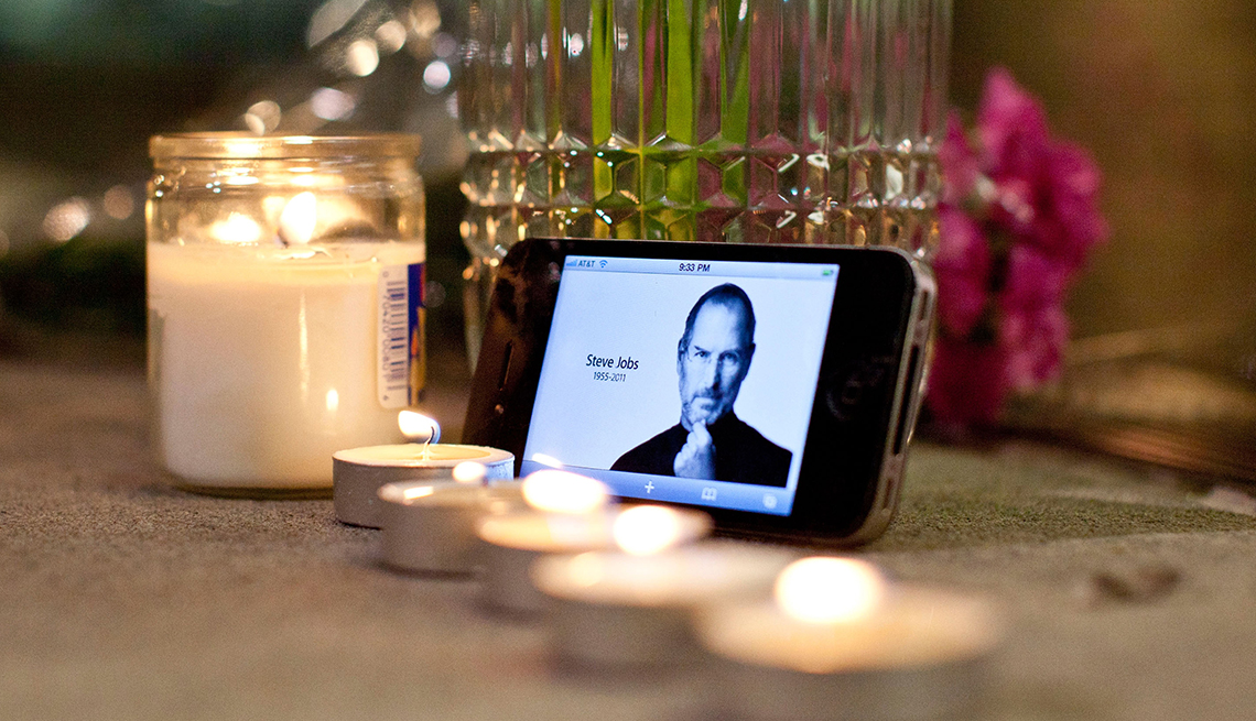 item 27 of Gallery image - Candles, flowers and an iPhone with Steve Jobs photo displayed, are seen in remembrance of Steve Jobs, founder and former CEO of Apple Inc.