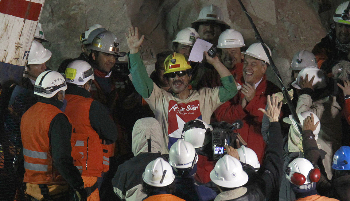 item 19 of Gallery image - Rescued miner Juan Andres Illanes Palma, center,  third miner to be rescued, salutes at his arrival to the surface from the collapsed San Jose gold and copper mine