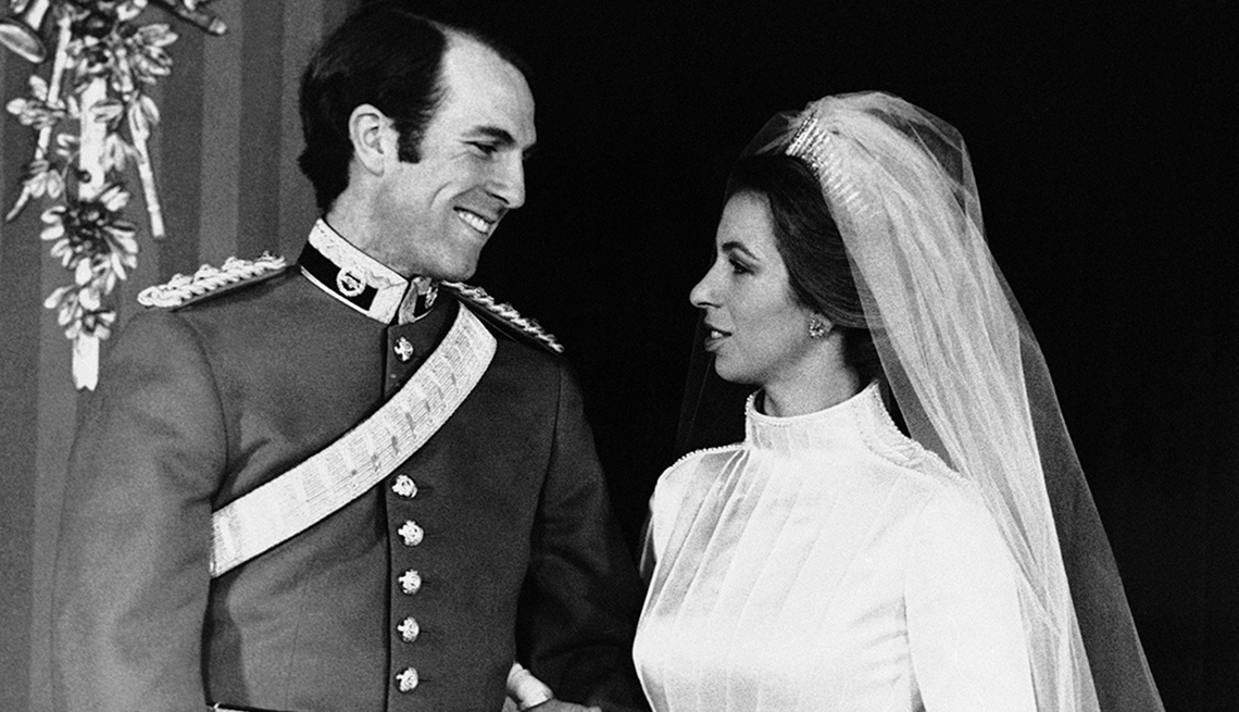princess anne in white outfit and veil and husband, captain mark phillips in suit smiling at each other