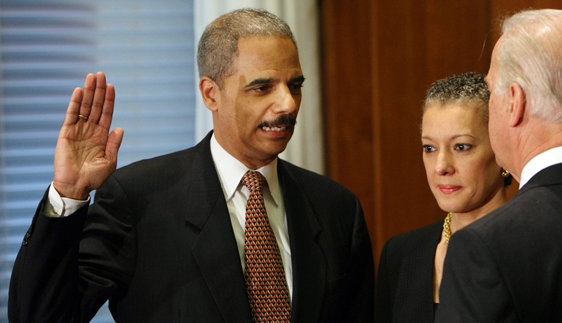 eric holder with right hand raised as he is sworn in by then vice president joe biden; holder's wife, sharon malone, stands next to him