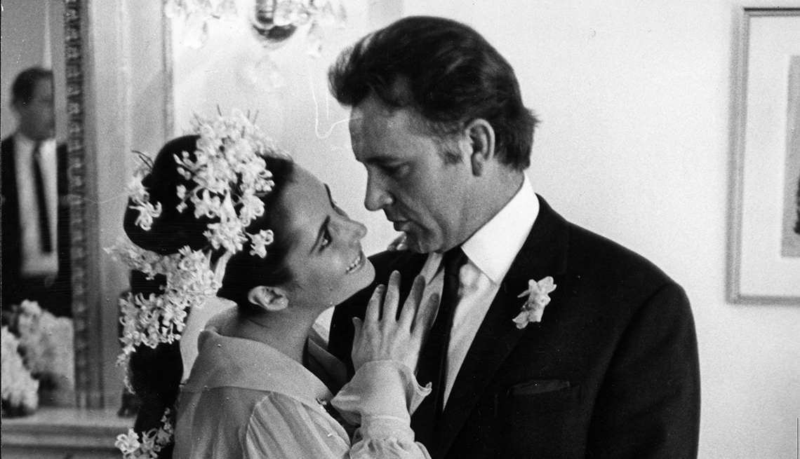 item 5 of Gallery image - elizabeth taylor in white dress, hand on richard burton's chest as he's dressed in a black suit; staring into each others eyes