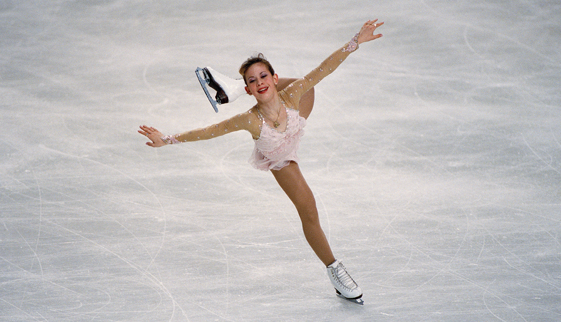 tara lipinski ice skating with one foot on ice and one bent in air behind her; arms out to sides