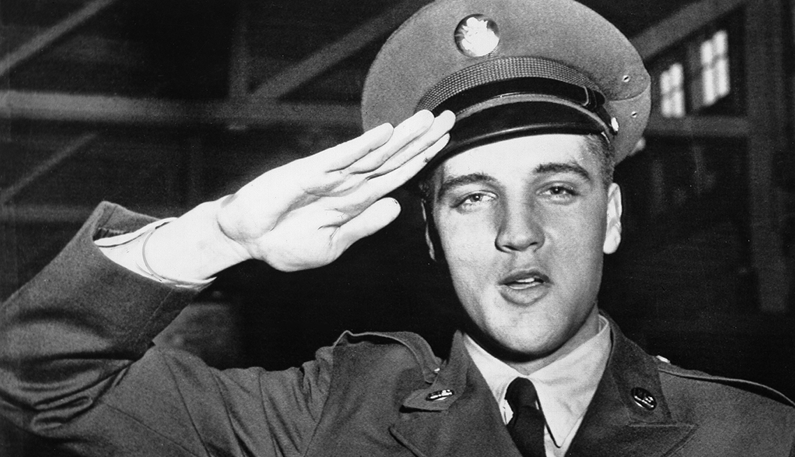 elvis presley in army uniform with right hand raised to head