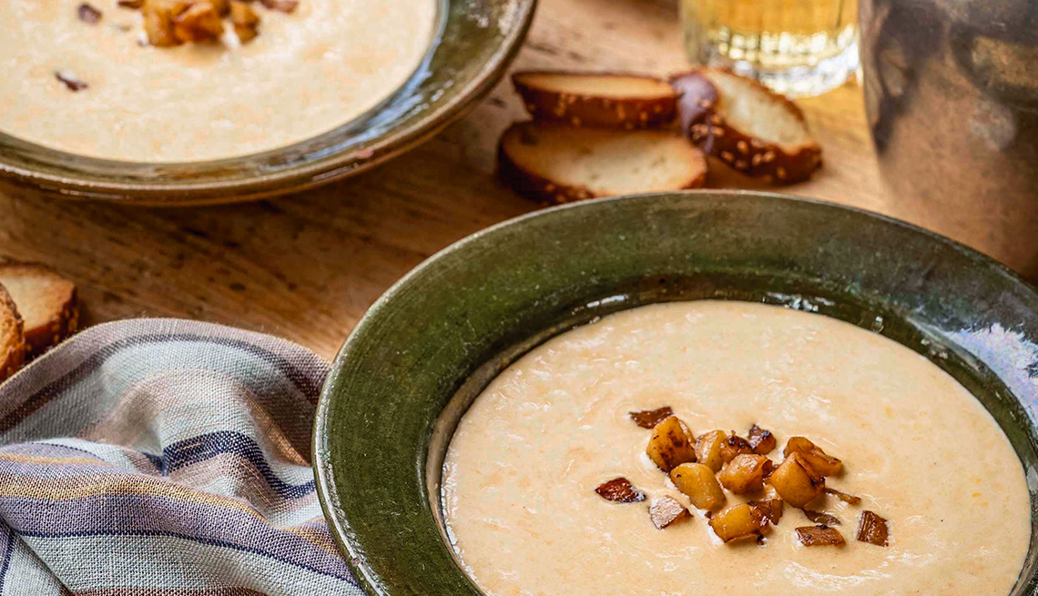 two bowls of creamy Hard Cider Cheese Soup With Sauteed Apples and Pretzel Croutons