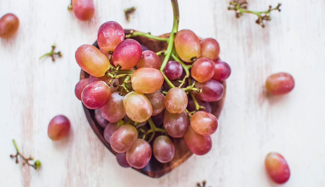 red grapes in and around a heart-shaped bowl