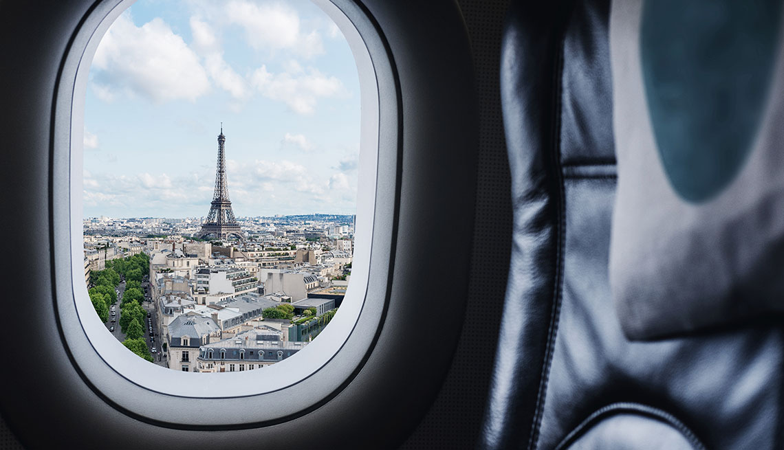 view of Paris and Eiffel Tower through window from empty airplane seat 