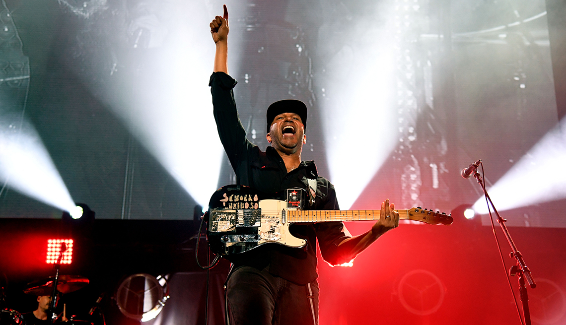 Tom Morello on stage holding an electric guitar and pointing to the sky