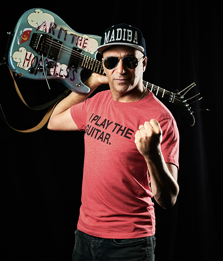 Tom Morello wearing t-shirt that says 'I play the guitar' and holding electric guitar over his shoulder
