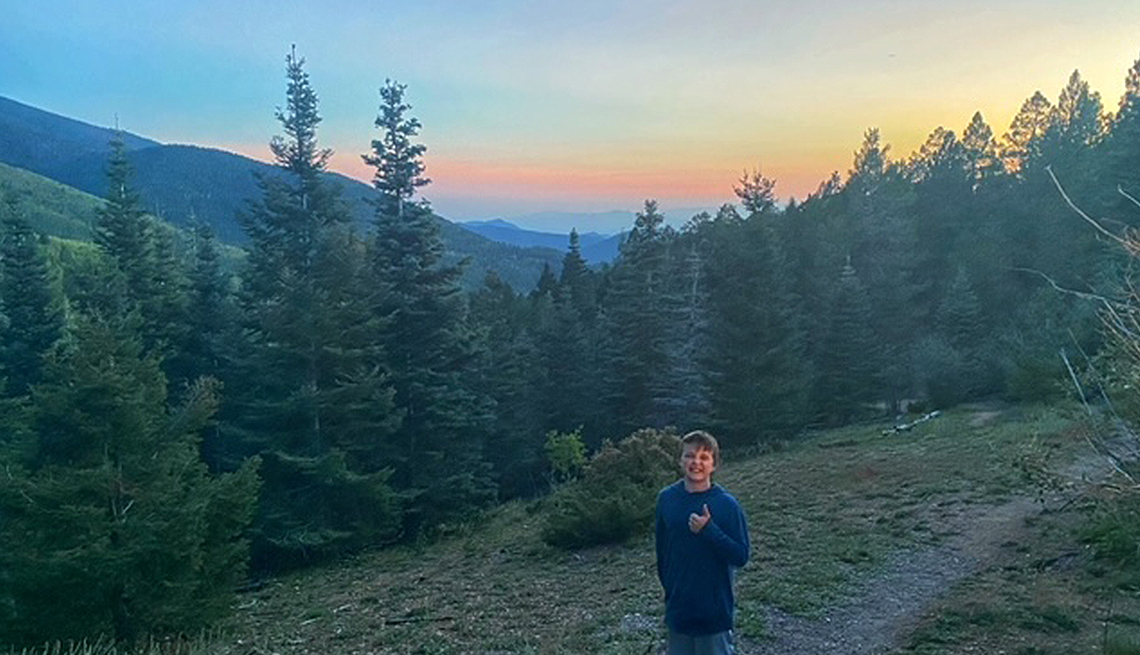 Terri Marshall’s grandson, Marshall, poses in front of the Rocky Mountains and trees