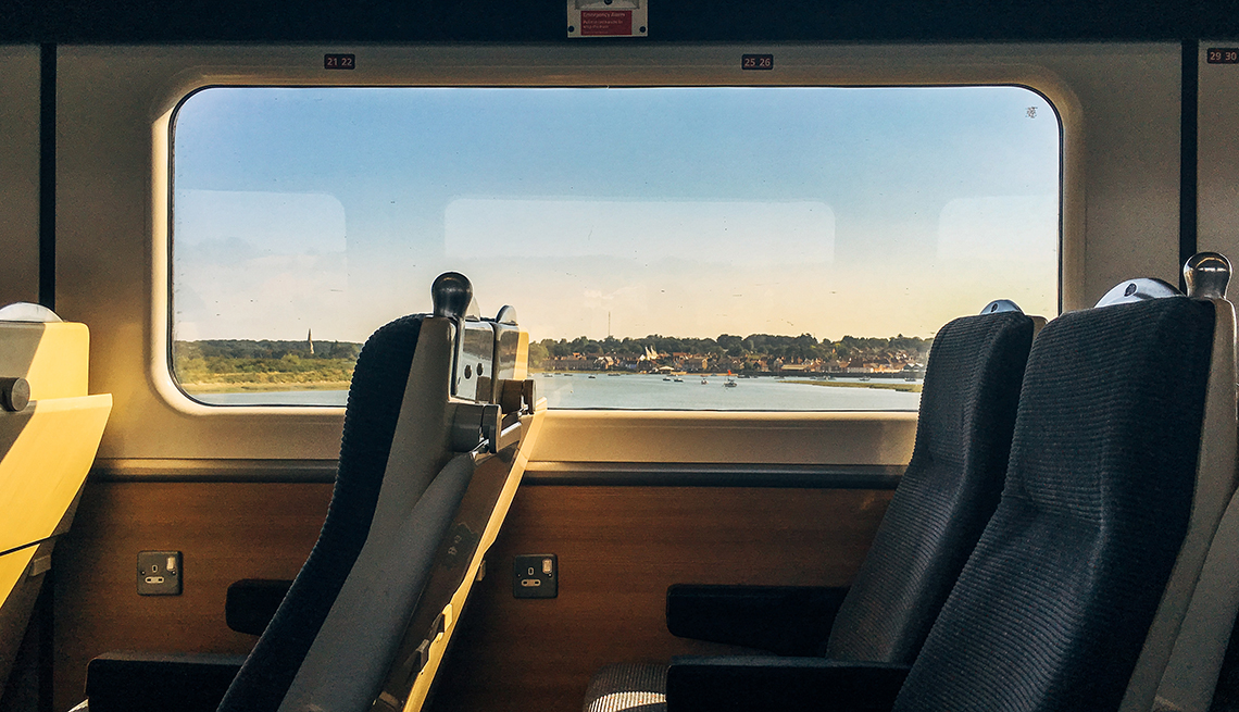 inside a passenger train with a window view of water and trees