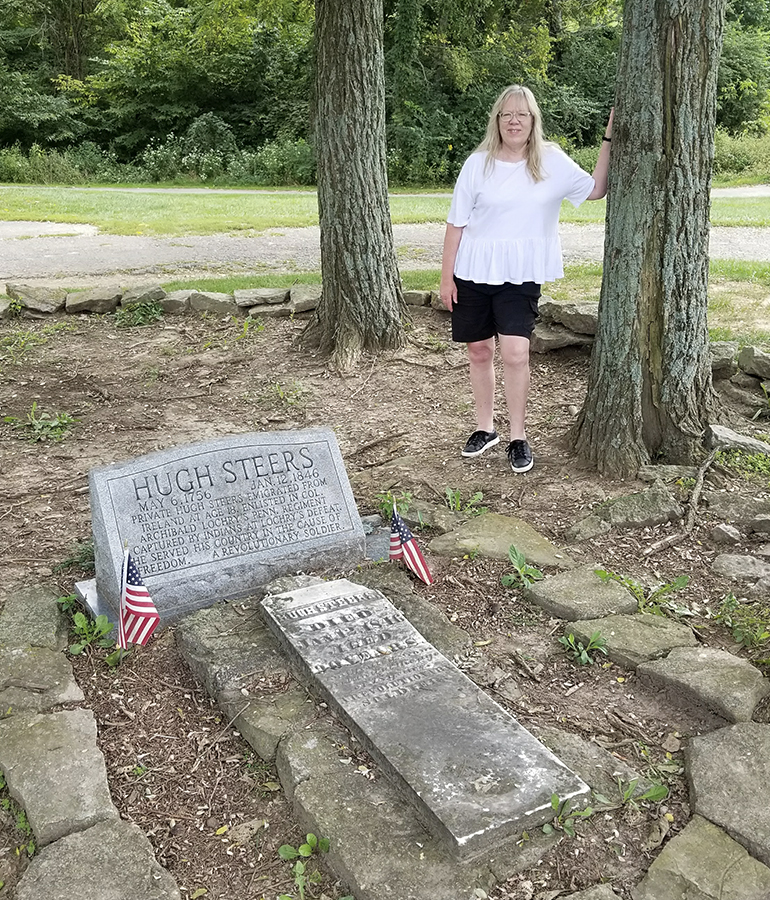 Author Gayle Keck stands behind Hugh Steers' gravesite