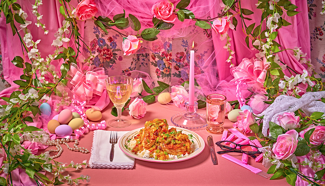 plate of chicken country captain in a very pink, very ornate setting with a glass of white wine, tall pink candle, pink and white flowers, pastel eggs, pink curtains and ribbon, black cat eye glasses, a lace glove, and more