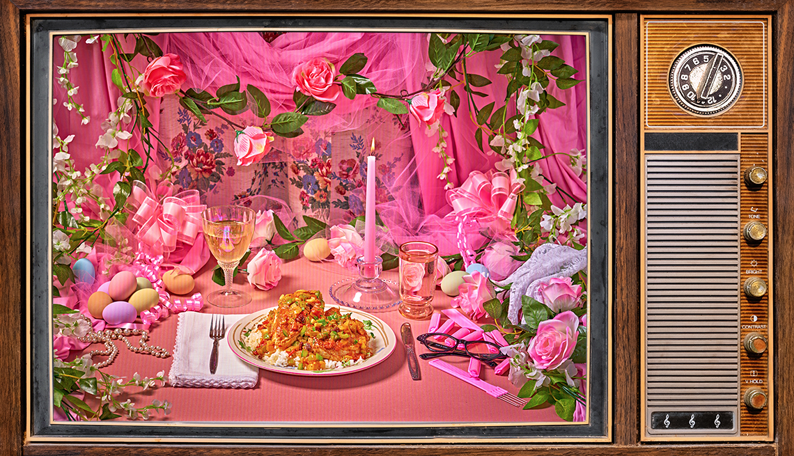 brown 1980s TV showing plate of chicken country captain in a very pink, very ornate setting with a glass of white wine, tall pink candle, pink and white flowers, pastel eggs, pink curtains and ribbon, black cat eye glasses, a lace glove, and more