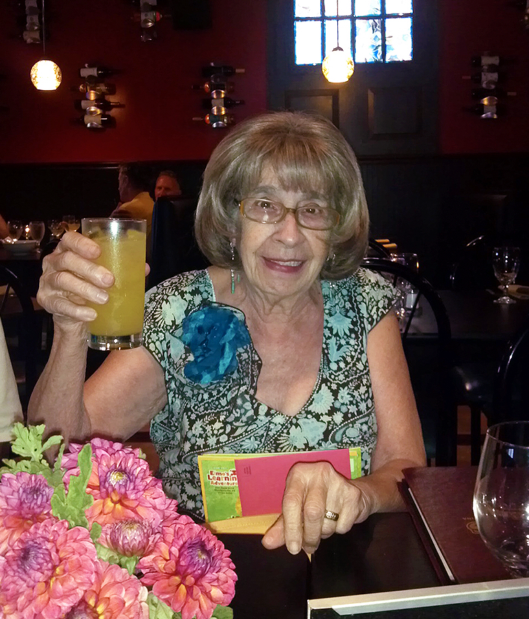Ann Hood's mother, Gogo, raising a drink in a dark restaurant