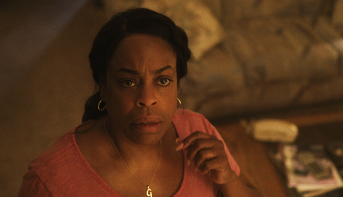niecy nash-betts as glenda cleveland standing in a living room looking up with a confused look on face in a still from dahmer monster the jeffrey dahmer story