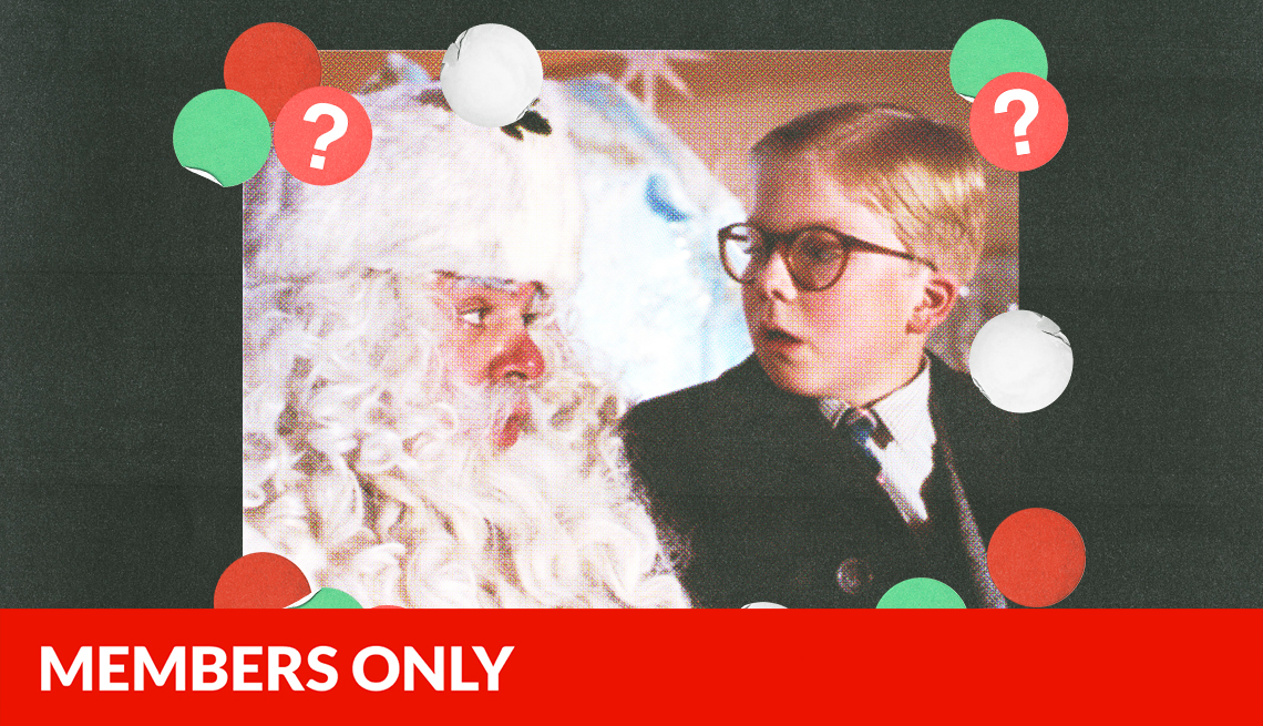 still from a christmas story of boy sitting on santa's lap and looking at him; red, green and white circles with question marks surround them; black background; red members only banner on bottom