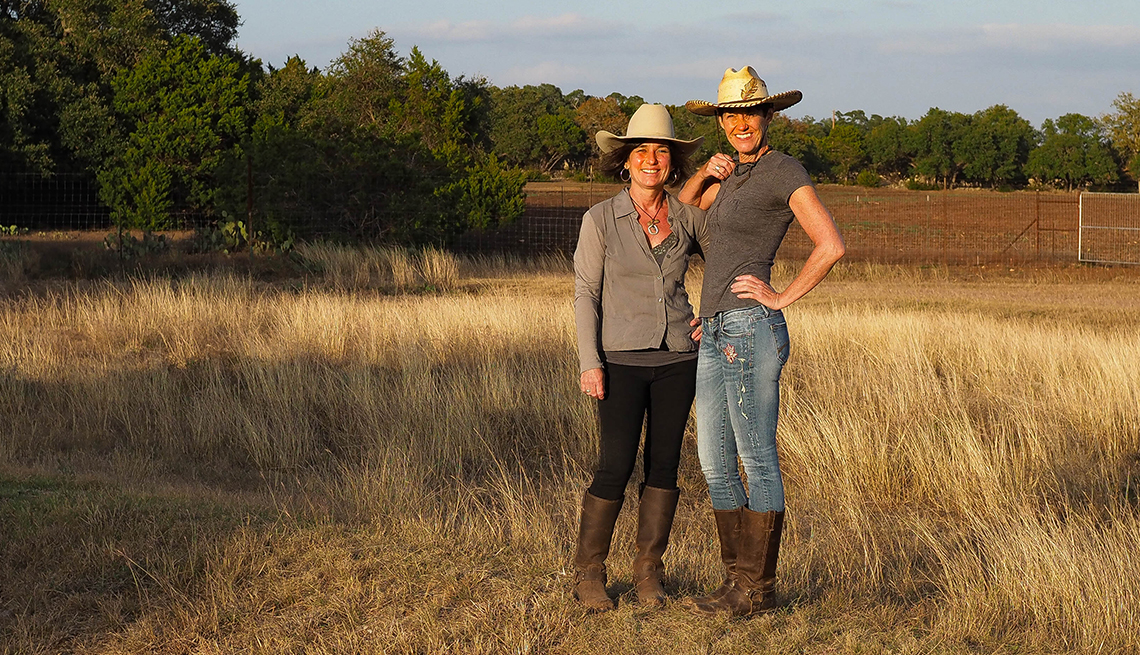 pam and marcy posing with each other wearing cowboy hats, standing in a field 