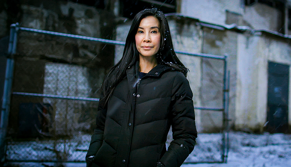 lisa ling standing outside in front of fence and building with coat on and snowflakes in hair