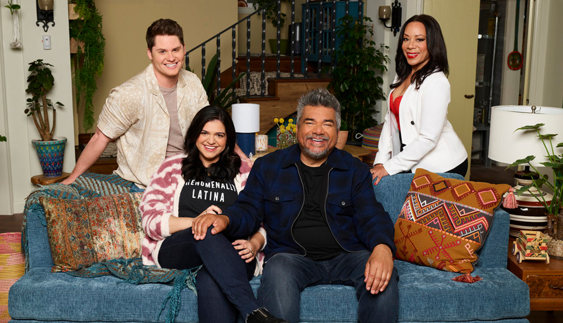 george lopez posing with matt shively, mayan lopez and selenis leyva on and around a couch on the set of lopez versus lopez