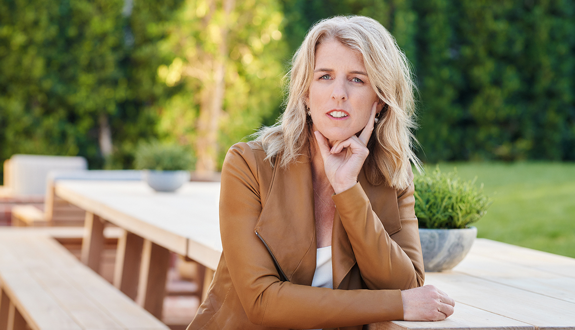 rory kennedy sitting on table outside in front of trees, hand holding chin