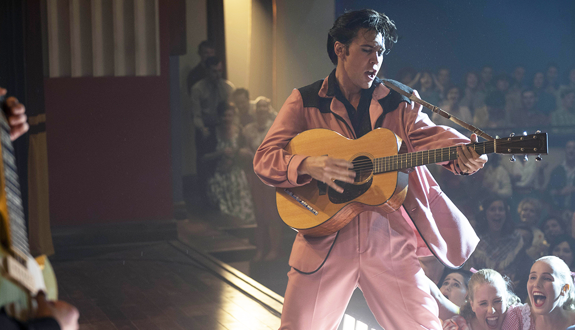 man playing guitar on stage in front of crowd in a still from elvis