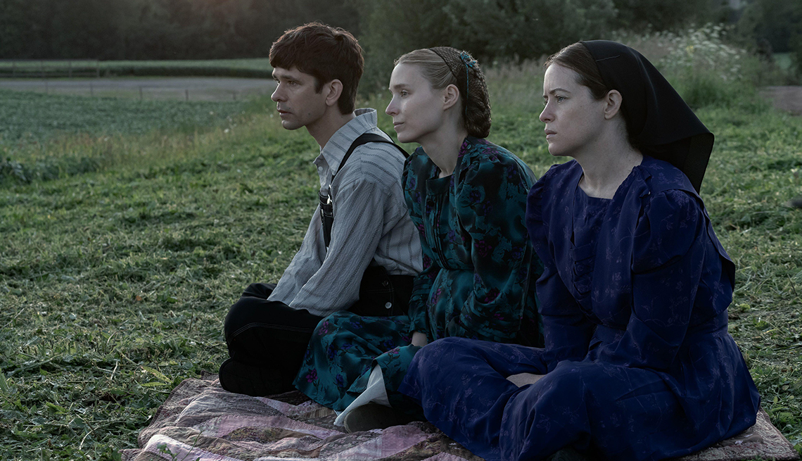 three people sitting on blanket in grass in a still from women talking