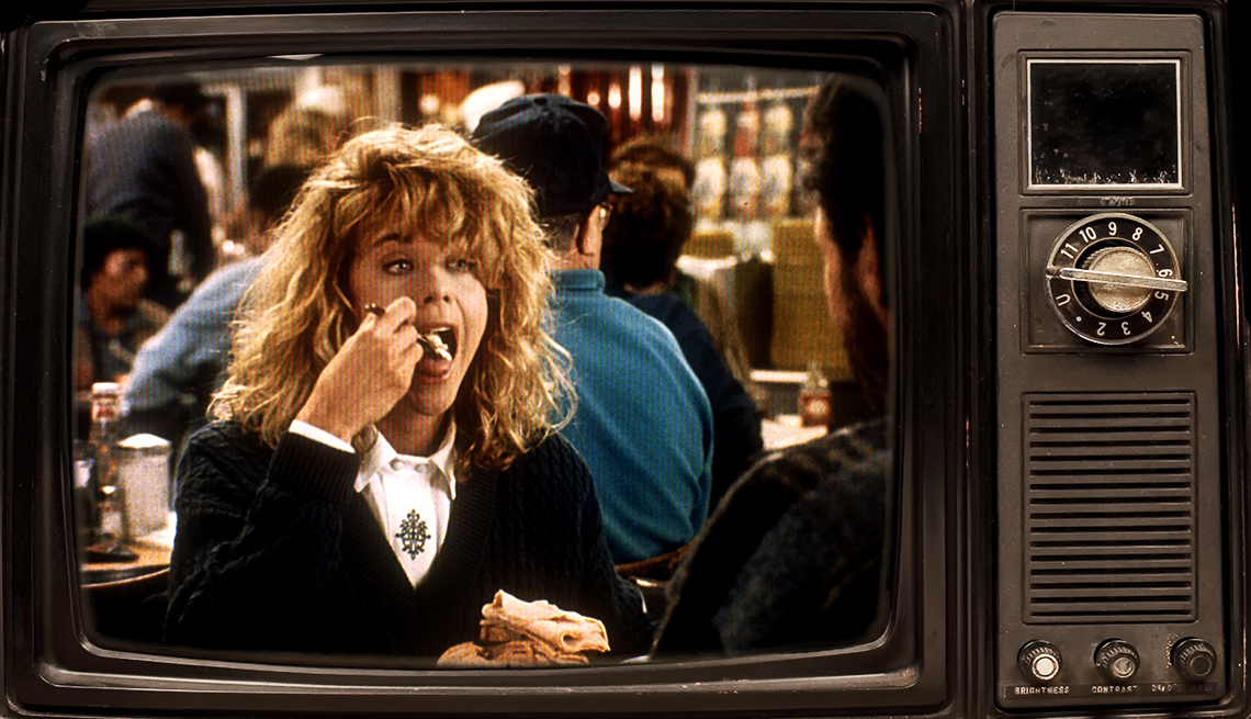 sally albright (meg ryan) sits across from harry burns (billy crystal) and puts a forkful of food in her mouth in famous diner scene from movie when harry met sally, 1980s-style television frames the scene