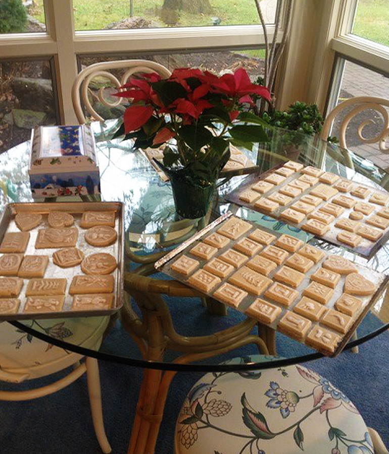 springerle cookies on pans on glass table with poinsettia in middle of table