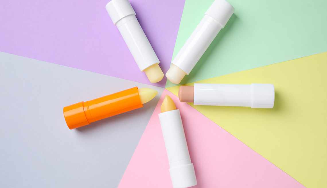 five chapsticks in a star formation with tops facing each other in the center; background is different pastel colors