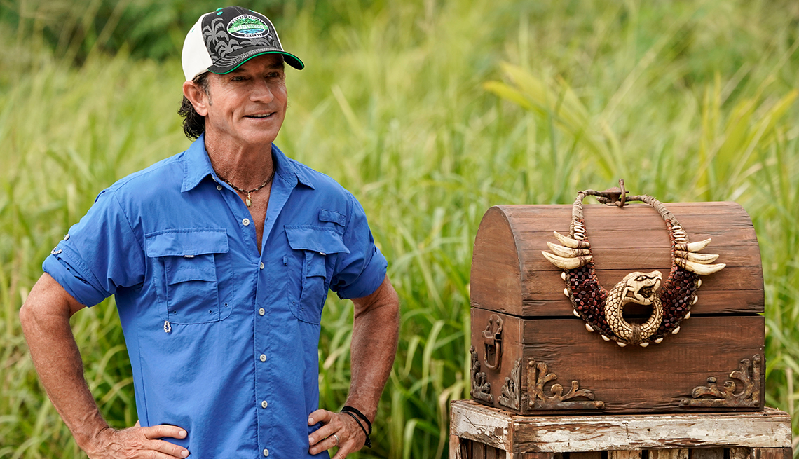 jeff probst on location standing next to a treasure chest in a grassy field