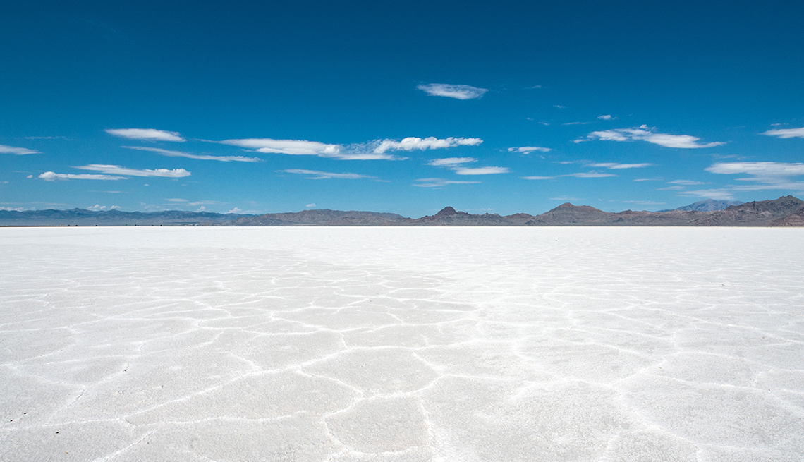beautiful white salt crust with mountains far away in the distance beneath a blue sky