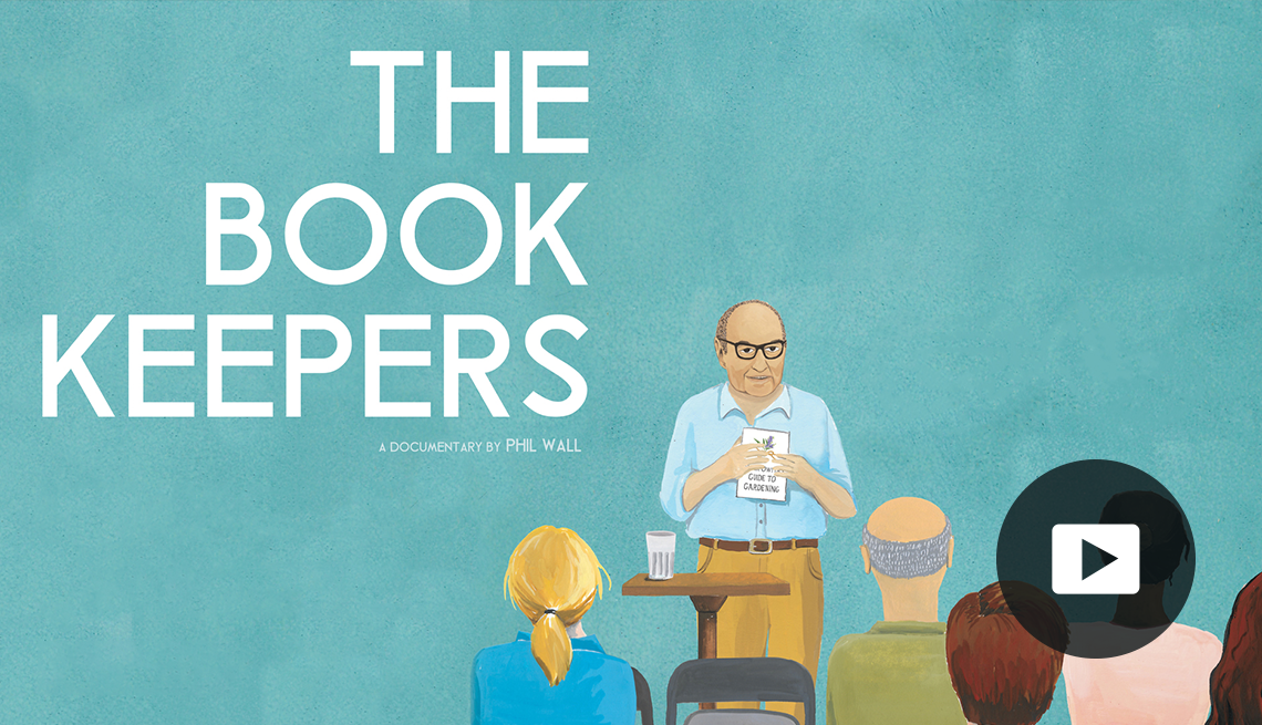 illustration of man holding book, facing forward towards people sitting in chairs; the words the book keepers are in top left quadrant; picture of play button in bottom right corner
