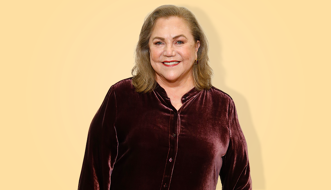 kathleen turner wearing brown shirt against peach colored background