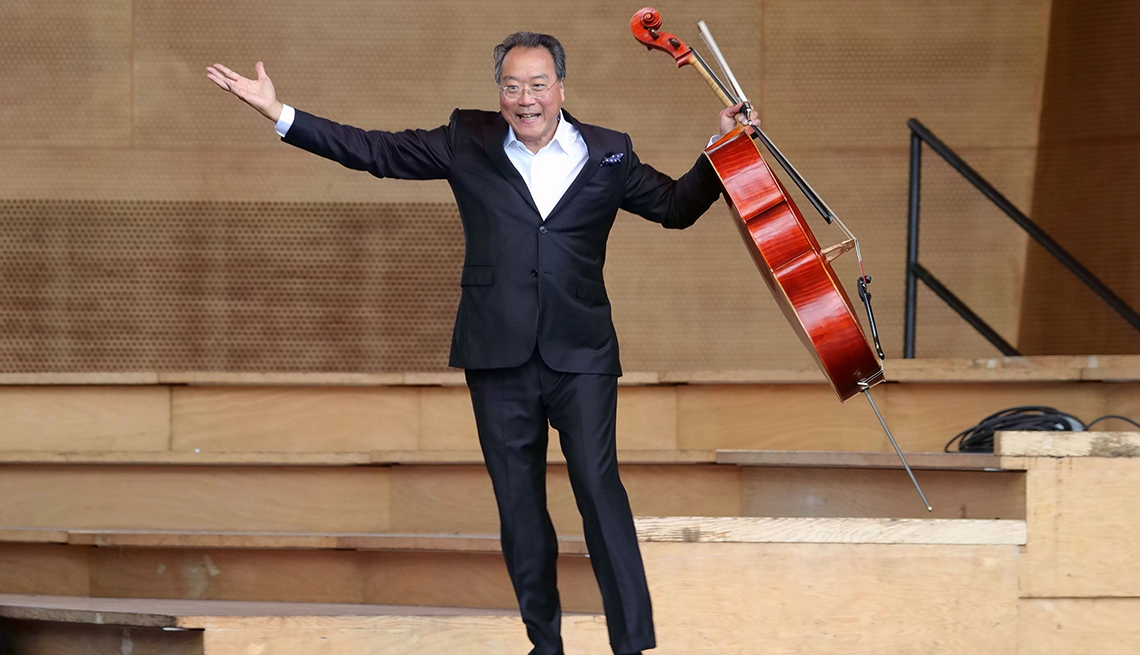 yo-yo ma on stage holding cello in left hand and other hand is out to the side
