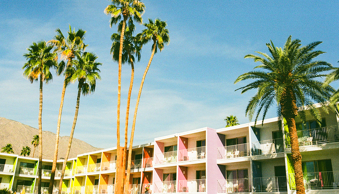 outside of hotel with balconies; palm trees in front