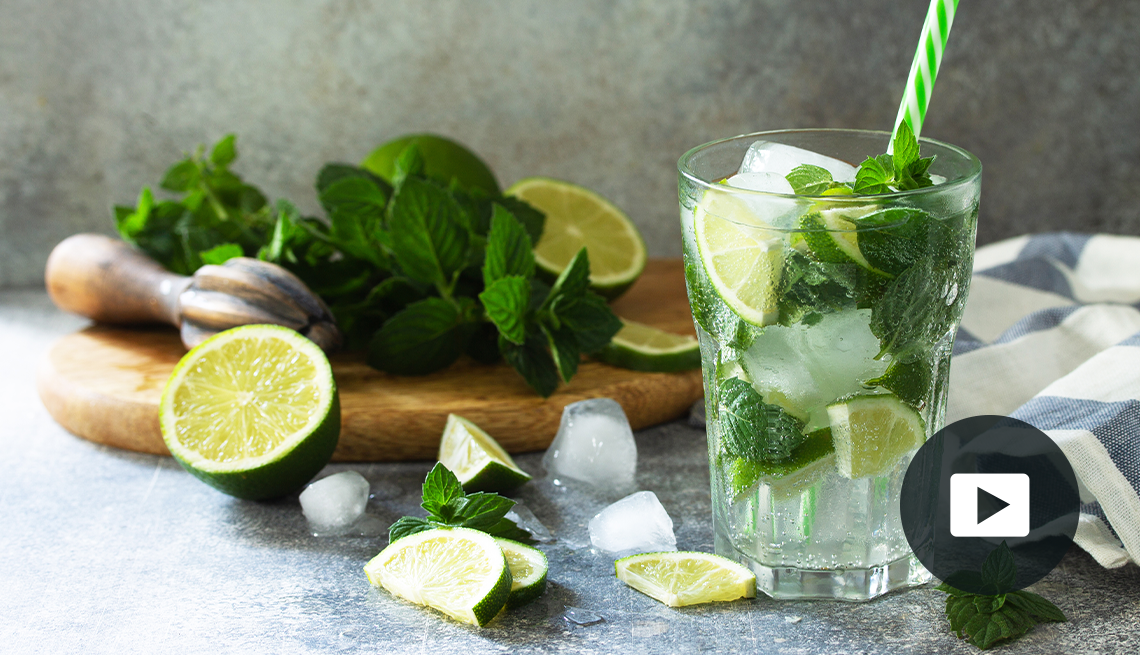 Fresh Mojito cocktail with lime, ice and mint in a glass on a gray stone background