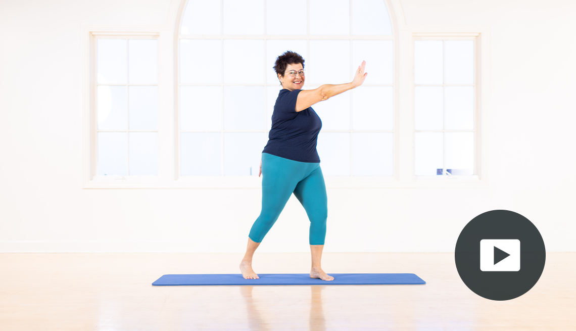 Karen Sanzo standing on mat doing Pilates; right arm pushing across body