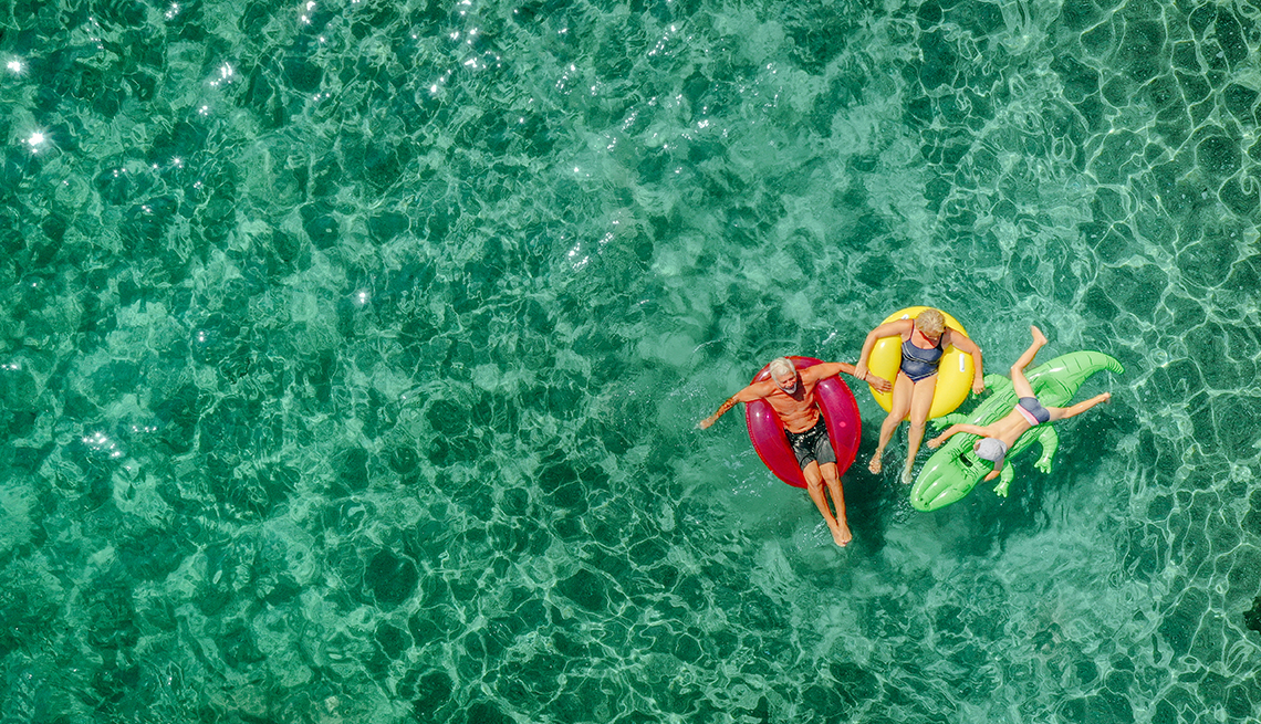 Two people sitting on tubes and one on a raft in water