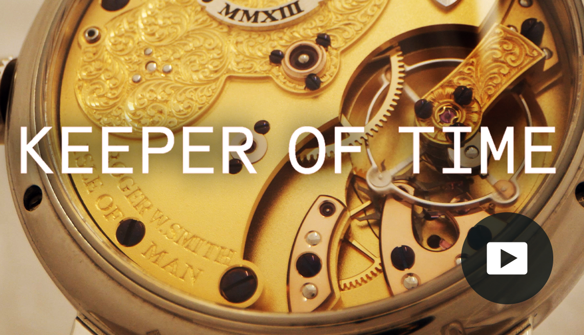 Close-up of gold watch, showing the inside of it; the words "Keeper of Time" across the middle