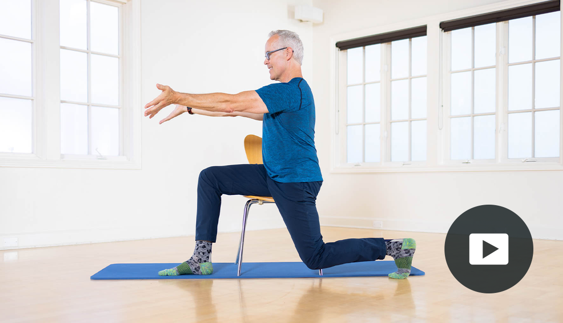 Tom McCook in lunge in front of chair doing Pilates with arms straight out in front of him