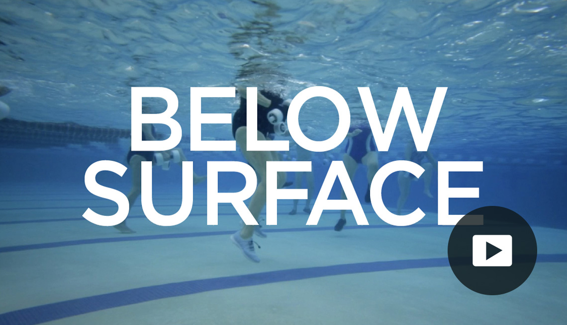 Underwater look at people in pool with words "Below Surface" across it