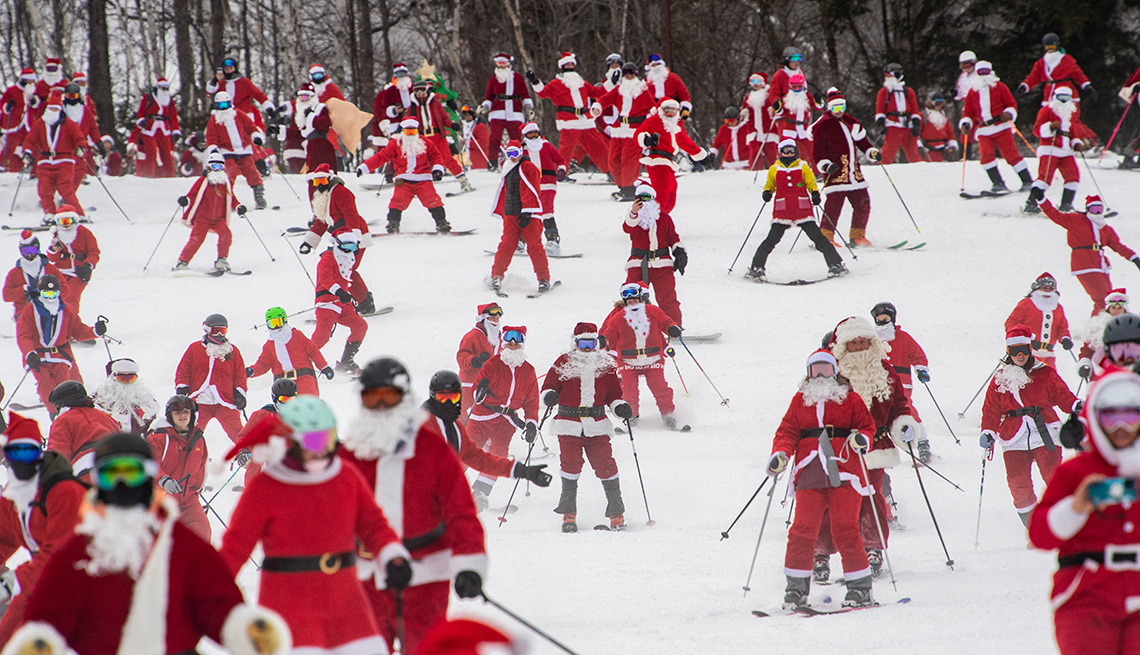 a ski slope crowded with people in santa costumes on skis 